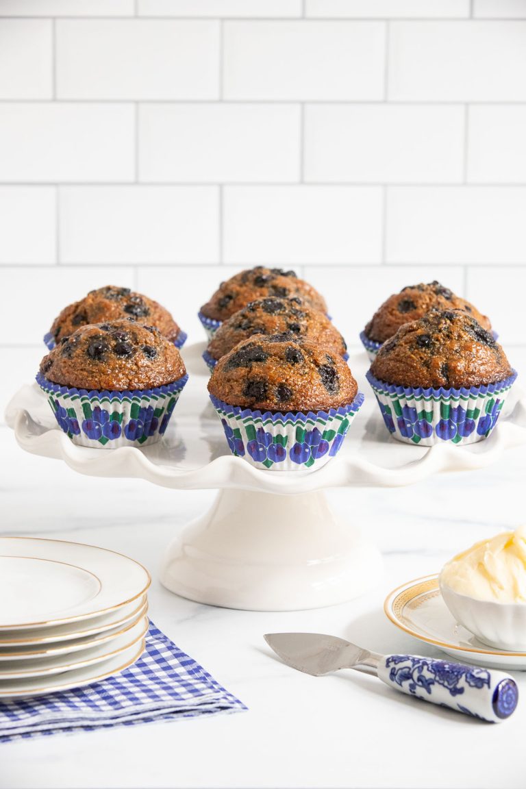 Vertical picture of blueberry bran muffins on a white cake stand