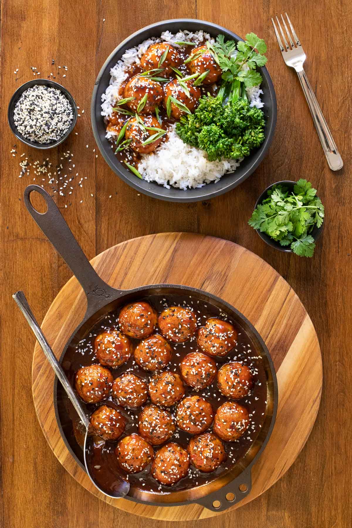 Vertical overhead photo of Huli Huli Chicken Meatballs in a cast iron skillet and in a serving bowl with rice and veggies.