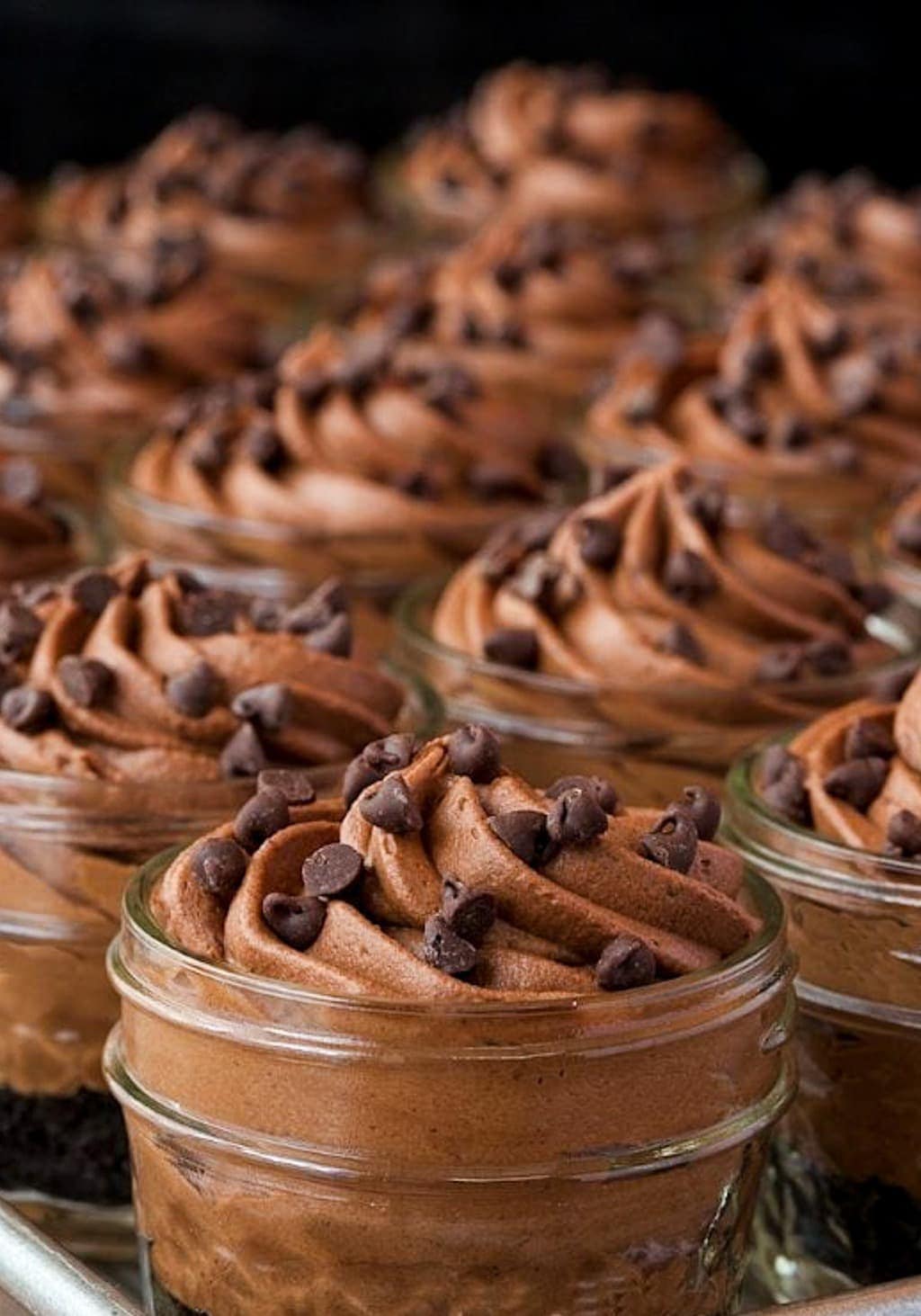 Photo of a batch of Irish Chocolate Cheesecakes in small canning jars garnished with mini chocolate chips.