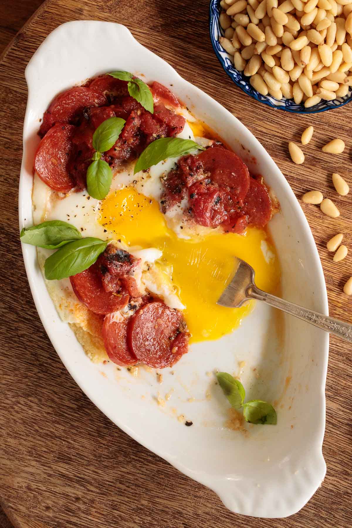 Overhead closeup photo of an individual baking dish of Italian Polenta Breakfast Casserole featuring the jammy egg consistency.