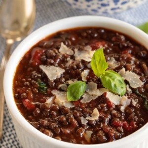 Vertical close up picture of Black Lentil Soup in a small white bowl