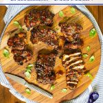 Overhead vertical closeup photo of Korean Honey Sesame Grilled Chicken sliced on a wood cutting board.