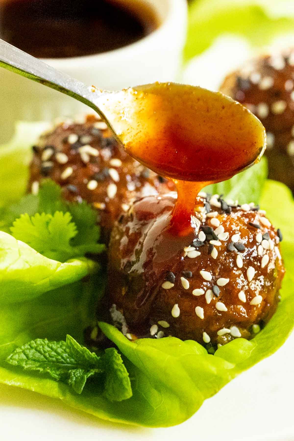 Close up vertical photo of Korean Meatball Lettuce Wraps with sauce being drizzled on top.