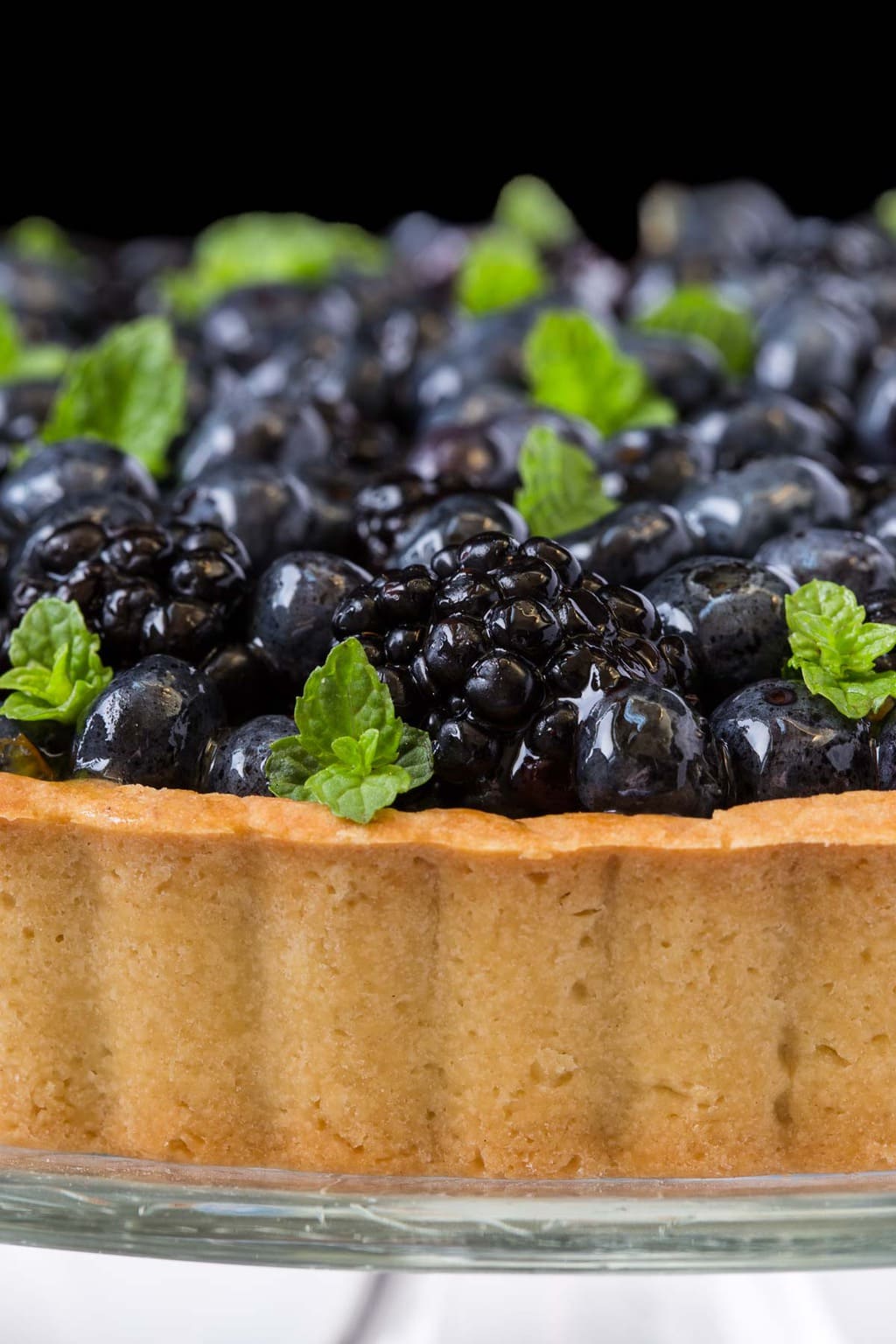 Ultra closeup photo of a Lemon Cheesecake with Glazed Berries, featuring the crust.