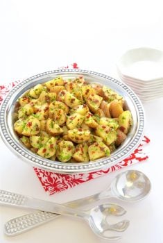 Vertical picture of Lemon, Rosemary and Sundried Tomato Potato Salad in a silver bowl on a red and white napkin