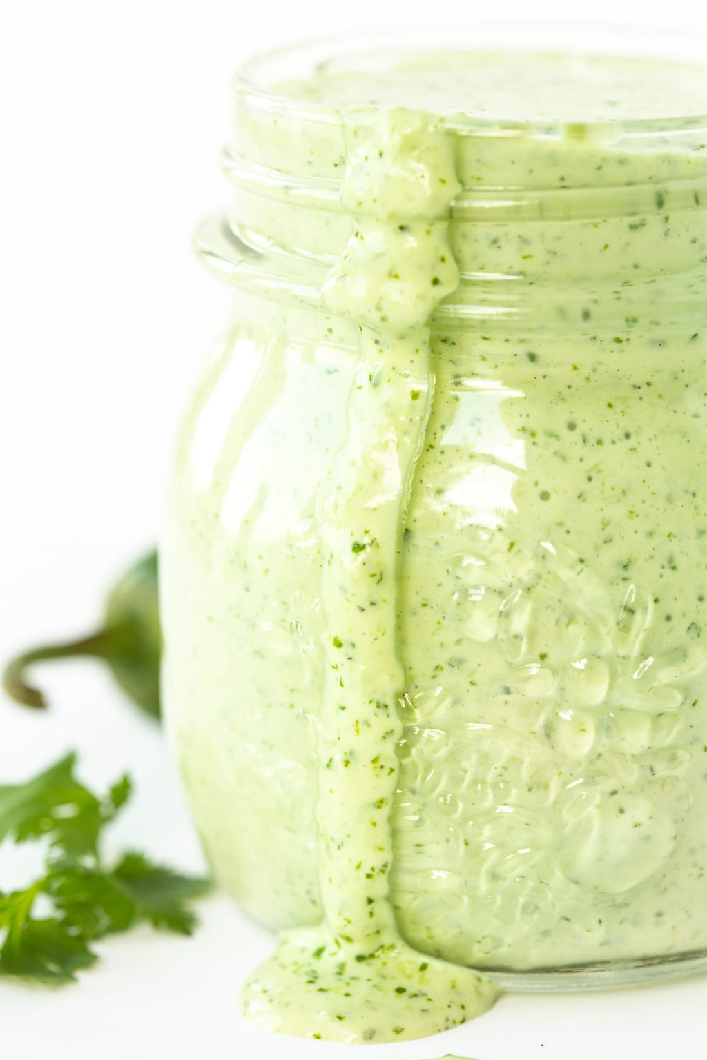 Vertical closeup photo of a glass jar filled with Light and Spicy Southwestern Cilantro Buttermilk Dressing.