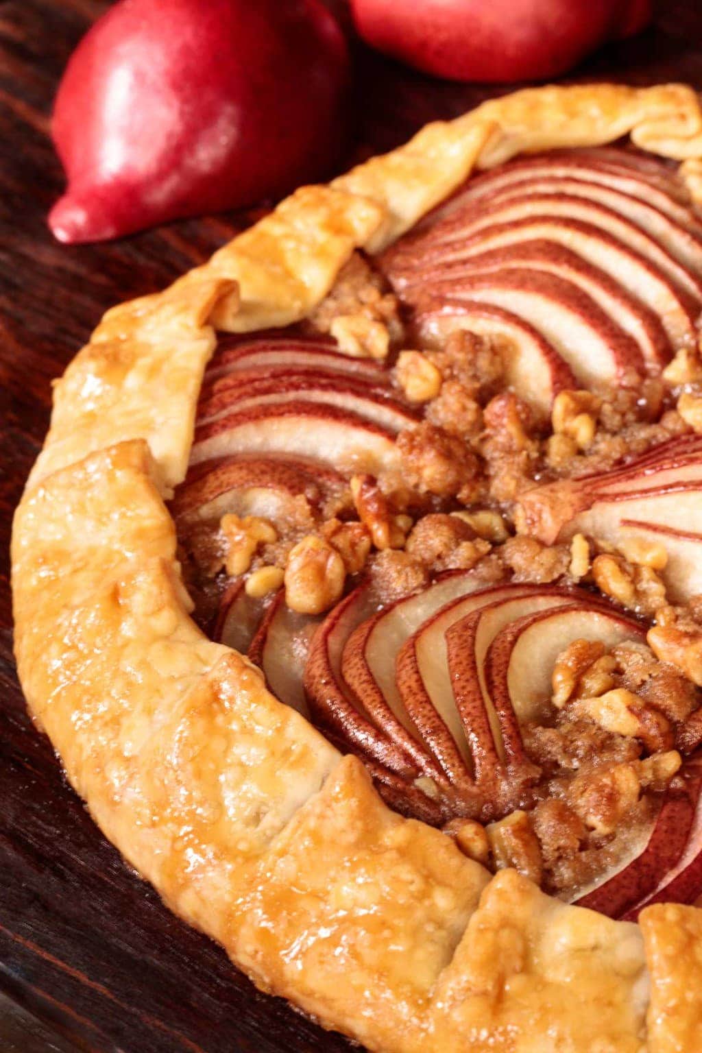 Vertical closeup photo of a Maple Glazed Red Pear Galette on a wood cutting board.
