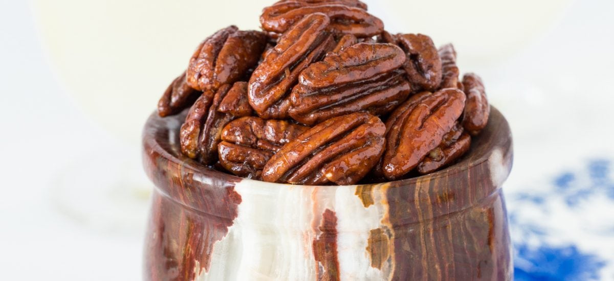 Vertical picture of Maple Molasses Glazed Pecans in a small stone bowl on a white background