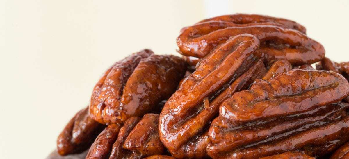 Maple Molasses Pecans - thecafesucrefarine.com Vertical closeup photo of Maple Molasses Glazed Pecans in a small marble bowl.