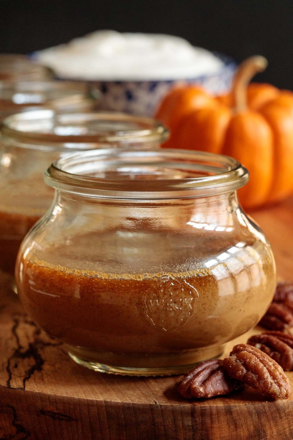 Closeup photo of a jar of Maple Pumpkin Pots de Crème on a wood platter.