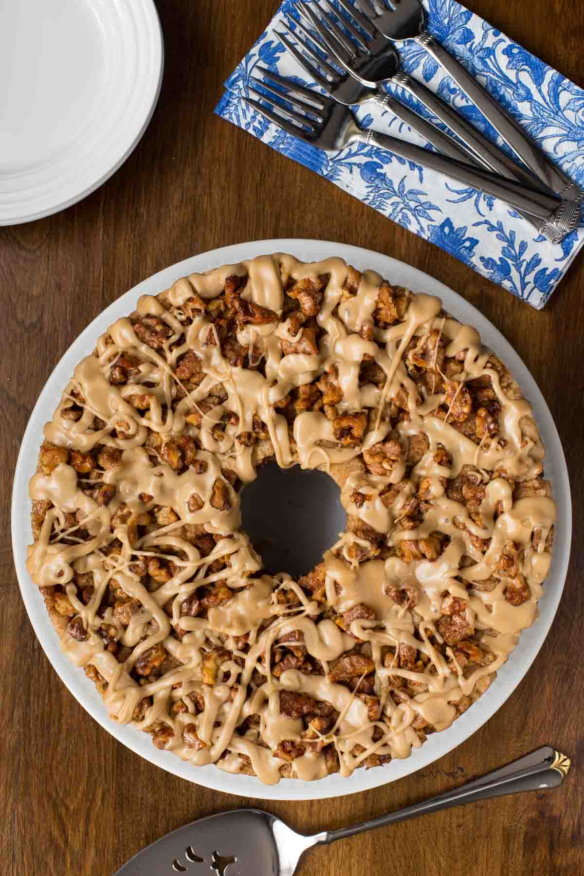 Overhead vertical photo of a Maple Walnut Banana Coffee Cake on a white plate with blue and white patterned napkins.