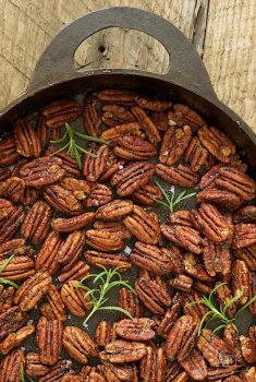 Vertical picture of maple rosemary pecans in an oval cast iron pan