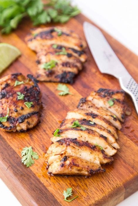 Vertical picture of Mexican Grilled Chicken sliced on a wooden cutting board