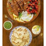 Overhead vertical photo of Middle Eastern Grilled Chicken with toum and zhoug sauces and pita bread.