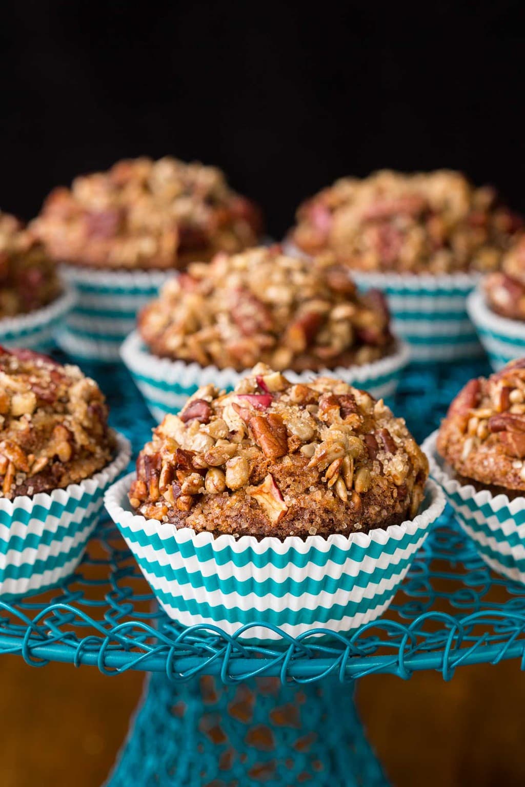 Photo of a turquoise wire cake stand filled with Candied Pecan Morning Glory Muffins in turquoise and white striped muffin cups.
