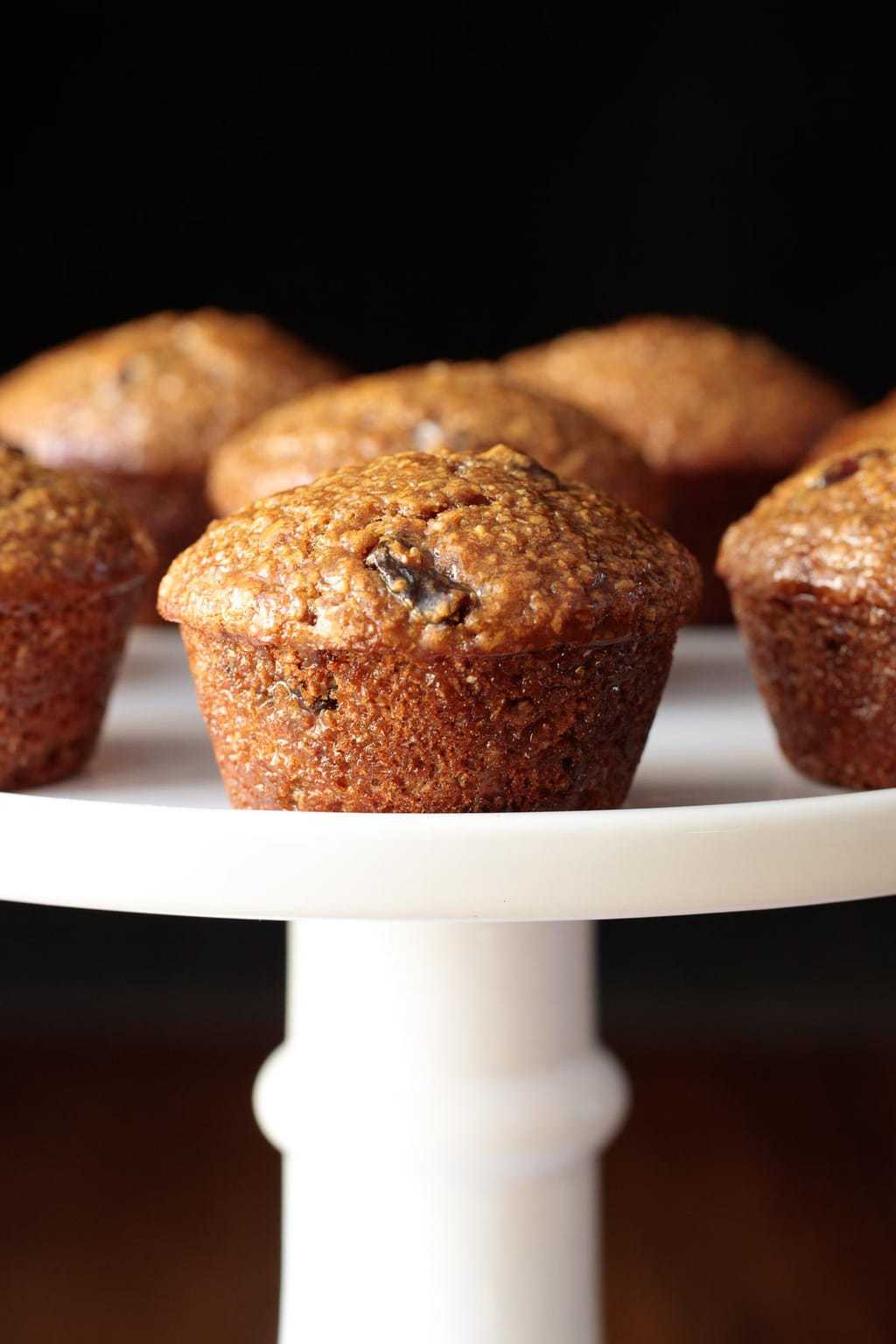 Vertical photo of One Bowl Buttermilk Bran Muffins on a white cake stand.