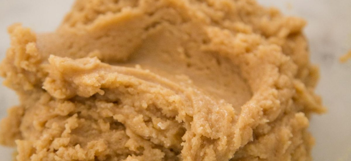 Shot of what the cookie dough should look like when making One Bowl Toffee Bar Chocolate Chip Cookies. The dough is in a clear bowl on a marble kitchen island.