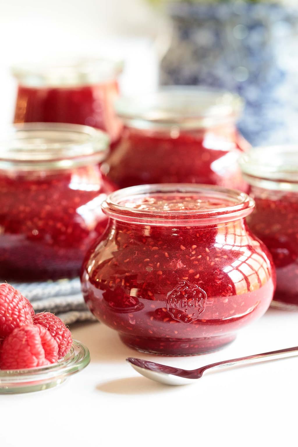 Vertical photo of a group of glass Weck jars filled with Raspberry Freezer Jam.