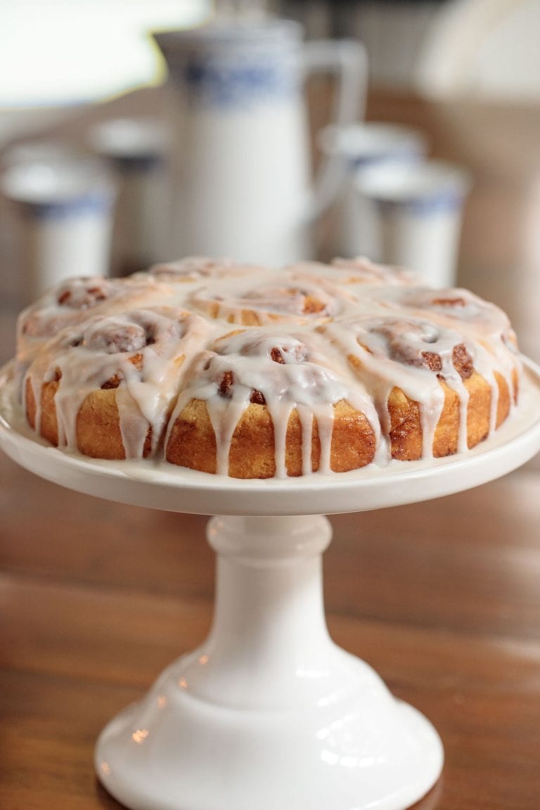Vertical picture of easy cinnamon rolls on a white cake stand