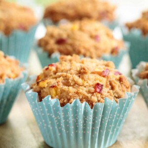 Vertical picture of peach crumble muffins in turquoise muffin liners