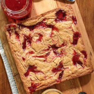 Overhead picture of peanut butter and jelly blondies on a wooden cutting board