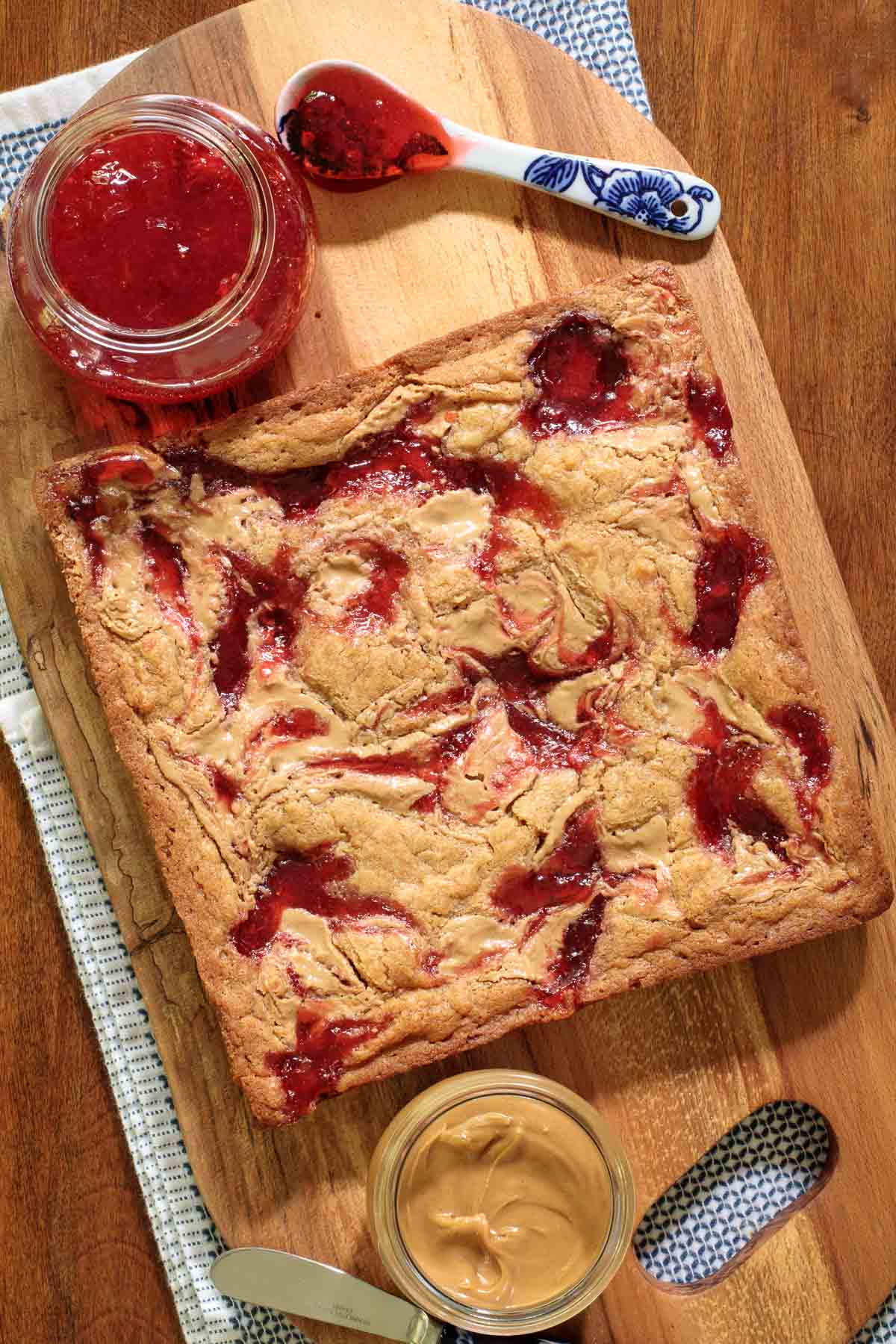Overhead picture of peanut butter and jelly blondies on a wooden cutting board