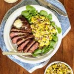 Overhead picture of perfectly grilled steak with corn salad on a wooden table