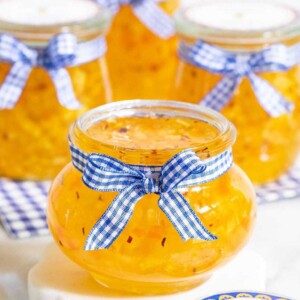 Vertical picture of Pineapple Habanero Pepper Jelly in small glass jars with blue and white ribbon