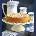 Vertical photo of a Almond Coconut Cake with title graphics at the bottom of the photo.