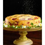 Vertical photo of a Ridiculously Easy Fresh Strawberry Cake on a rustic wood pedestal cake stand with powdered sugar being lightly sprinkled on the top.