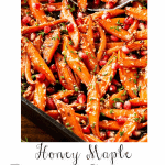 Extreme closeup photo of a batch of Honey Maple Roasted Carrots in a cast iron baking pan.