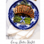 Vertical overhead photo of a plate of Prosciutto-Wrapped Chicken Breasts with a serving of grilled asparagus spears beside the sliced breasts.