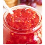 Vertical extreme closeup photo of the top of a jar of Strawberry Habanero Pepper Jelly.