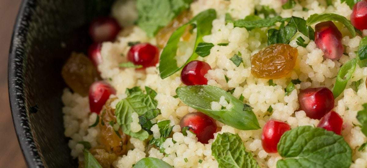 Overhead photo of a black bowl filled with Pomegranate Parsley Couscous Salad.