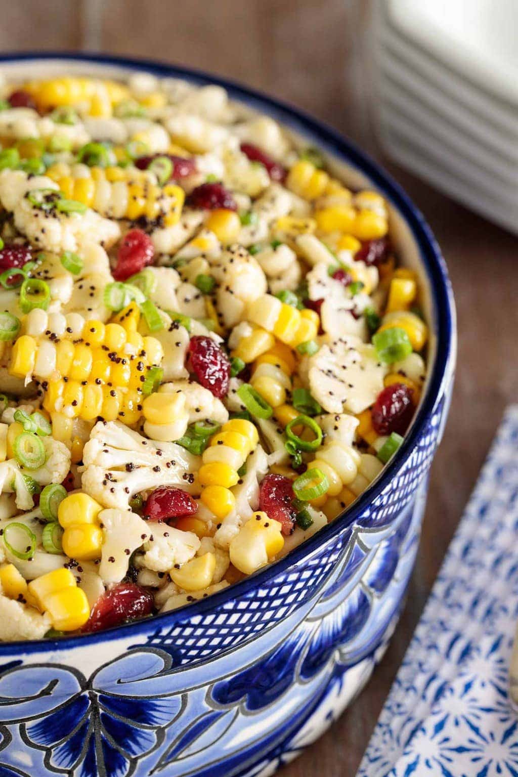 Photo of half of a blue and white patterned serving bowl filled with Poppyseed Cauliflower and Fresh Corn Salad