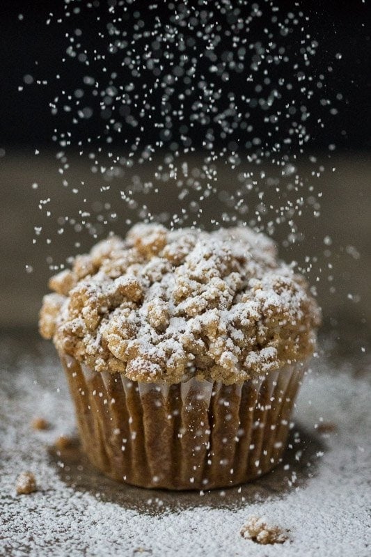 Vertical picture of Pumpkin Crumb Muffin on a black background with powdered sugar on top