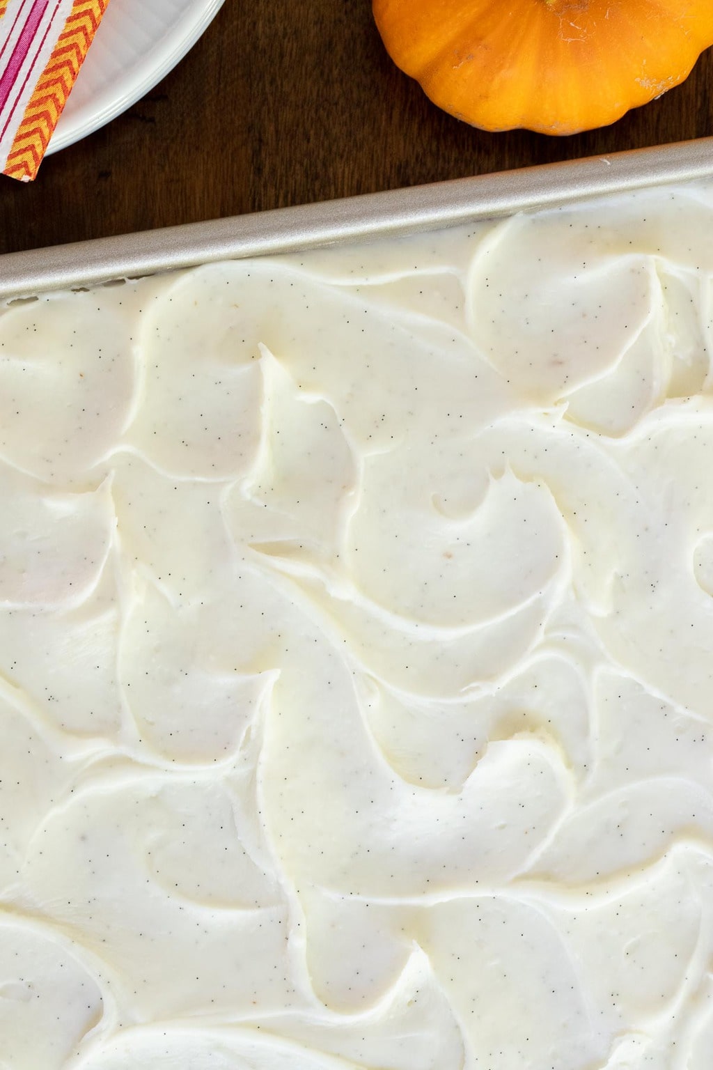 Overhead vertical closeup photo of a One-Bowl, No-Mixer Pumpkin Sheet Cake featuring the swirl vanilla bean frosting.