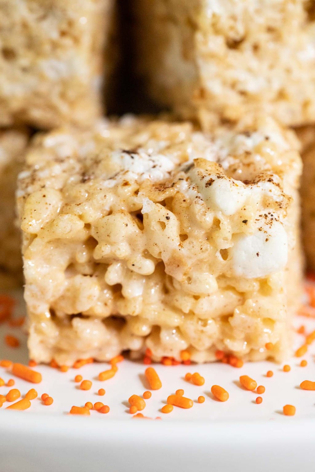 Vertical closeup photo of a plate of Pumpkin Spiced Brown Butter Rice Krispie Treats stacked on top of each other.