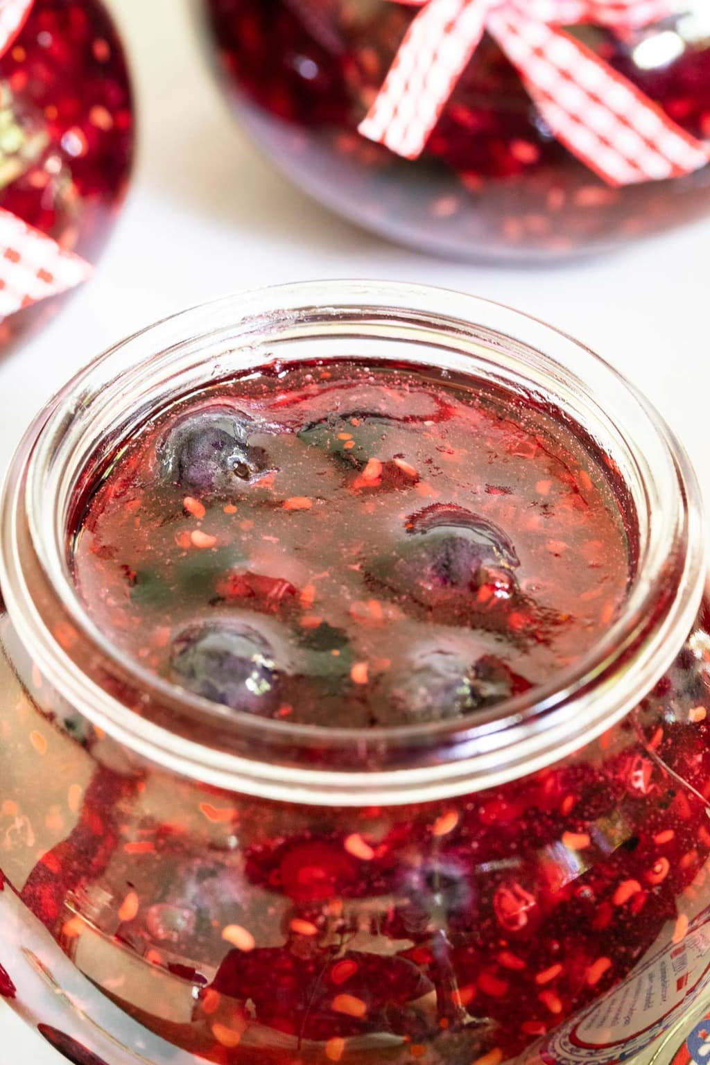 Closeup vertical photo of a jar of Queen's Jam (Raspberry Blueberry Jam).