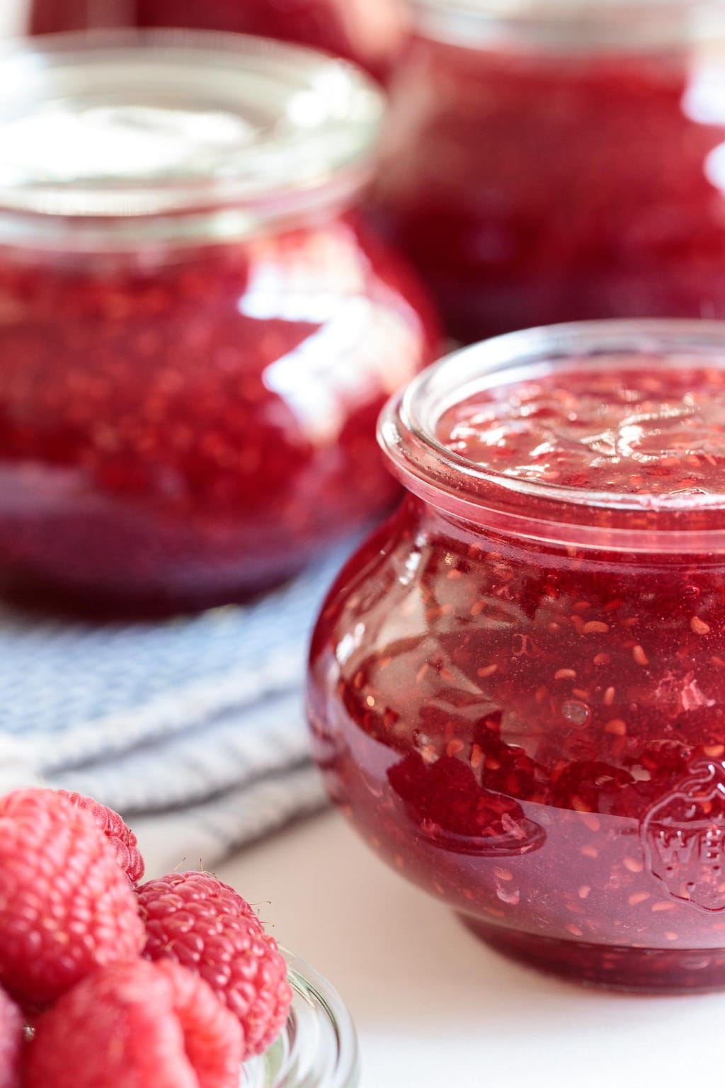 Vertical closeup photo of Weck canning jars filled with Easy Raspberry Freezer Jam.