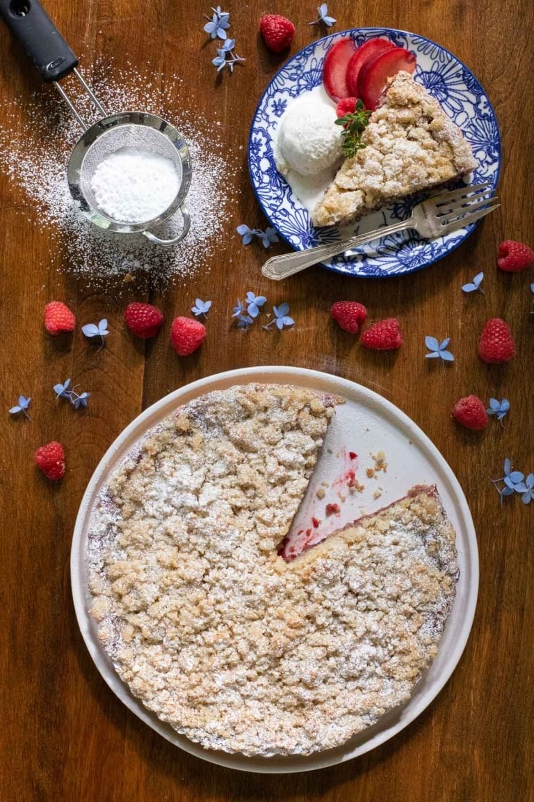Overhead picture of Raspberry Plum Crumb Tart with a slice cut out on a plate