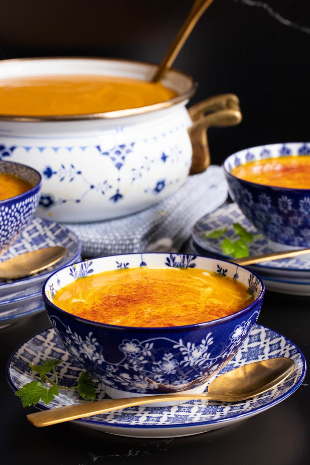 Vertical closeup photo of Red Lentil Carrot Ginger Soup in blue and white patterned serving bowls.