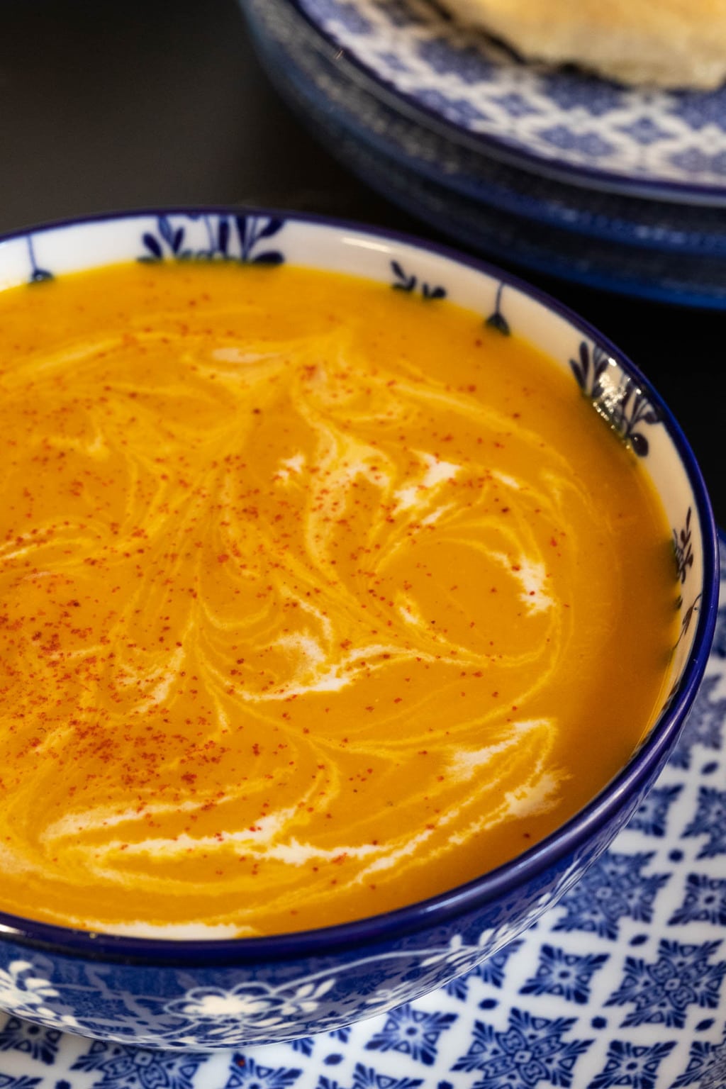 Vertical extreme closeup photo of a blue and white patterned bowl of Gingery Red Lentil Carrot Soup.