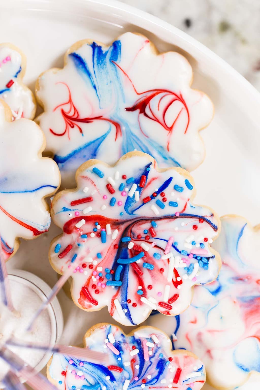 Overhead vertical closeup photo of a serving plate of Red, White, and Blue Glazed Shortbread Cookies.