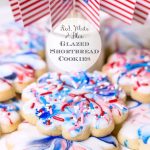 Vertical closeup photo of a batch of Red, White, and Blue Glazed Shortbread Cookies decorated with U.S. flags and a circle text graphic in the center.