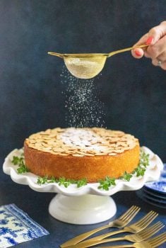 Vertical picture of Easy Almond Coconut Cake being dusted with powdered sugar