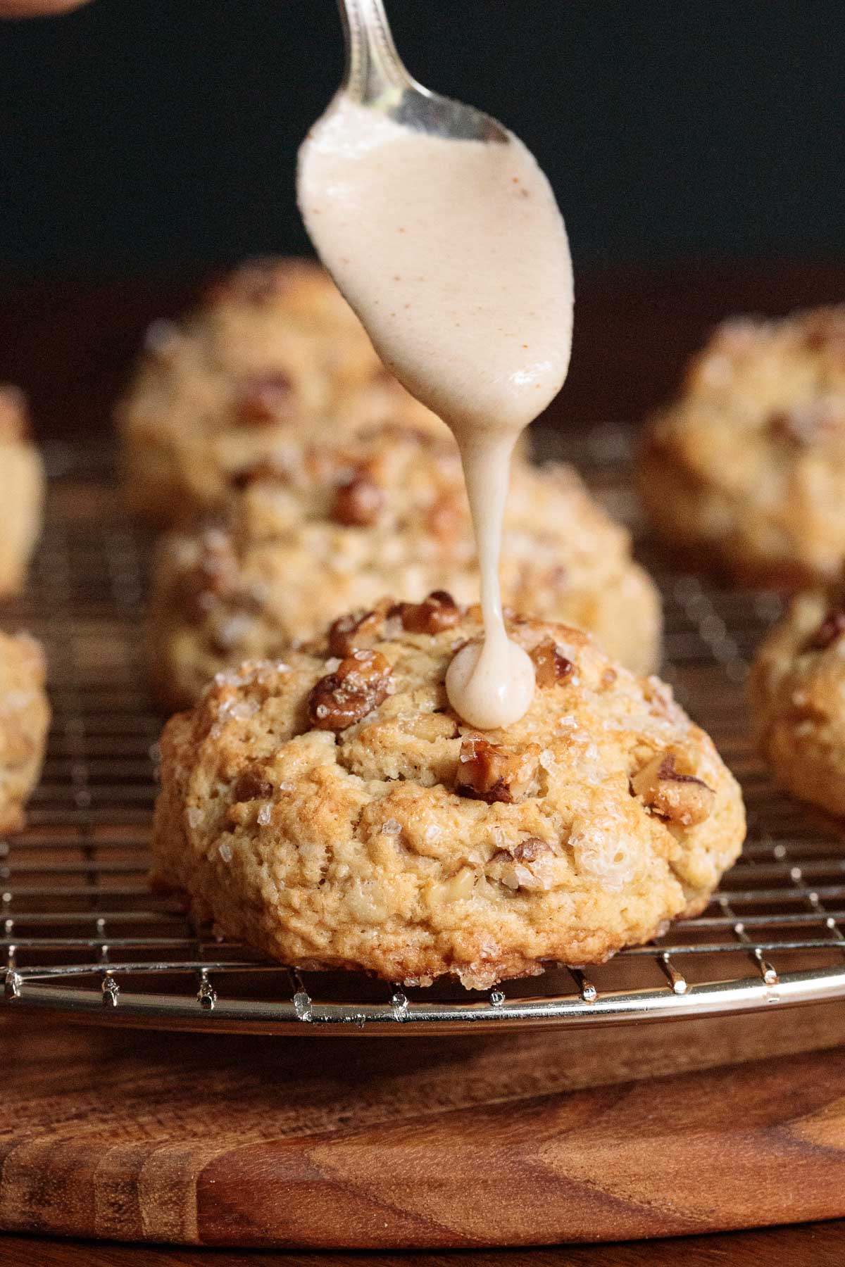 Vertical closeup photo of Ridiculously Easy Banana Bread Scones on a chrome cooling rack with icing drizzled on top.