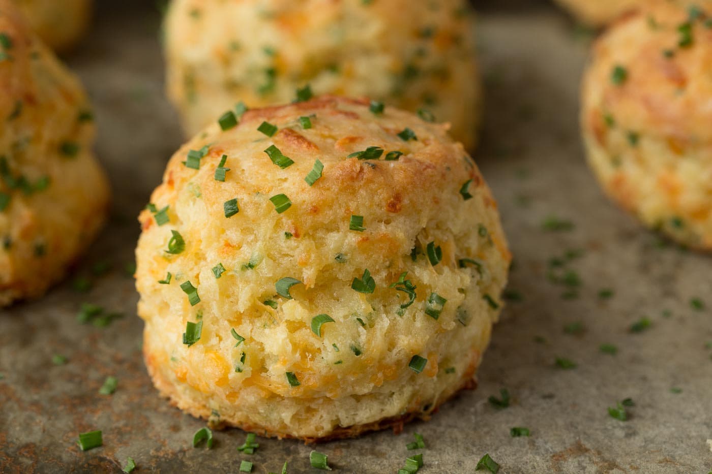 Photo of rows of Ridiculously Easy Cheddar Chive Biscuits on a slate surface
