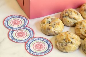 Chocolate Cherry Scones sitting on a countertop with custom labels and a bright pink box in the background