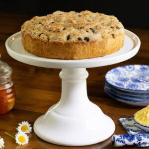 Horizontal photo of Ridiculously Easy Cinnamon Raisin Focaccia on a white pedestal serving plate.
